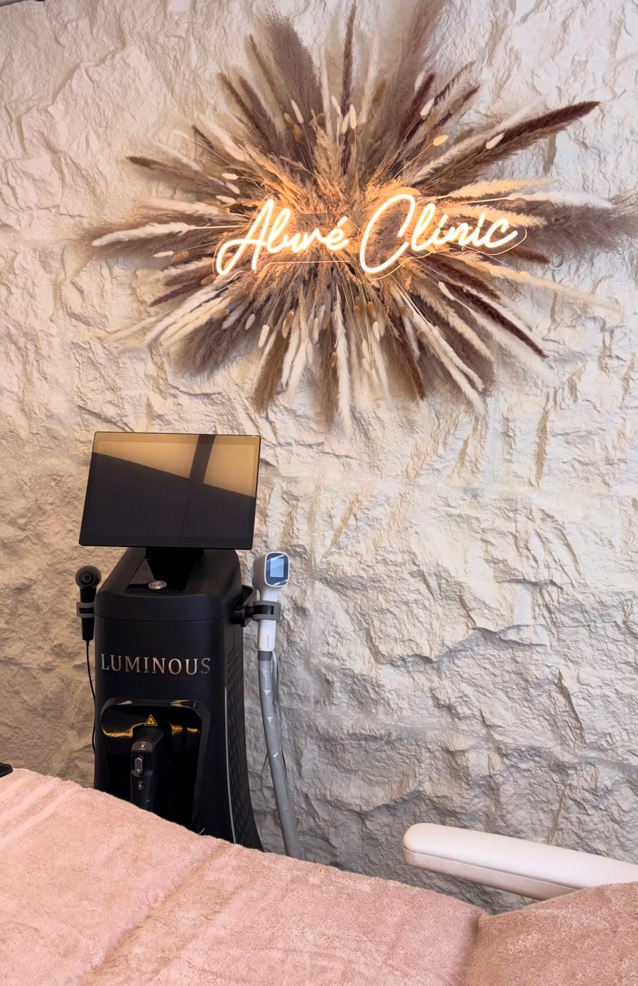 Behandelkamer van Aluré Clinic met neon logo en diodelaser